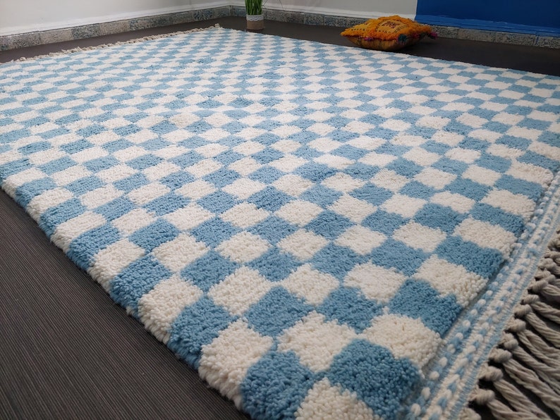 May include: A blue and white checkered rug with a fringe border. The rug is made of a soft, fluffy material.