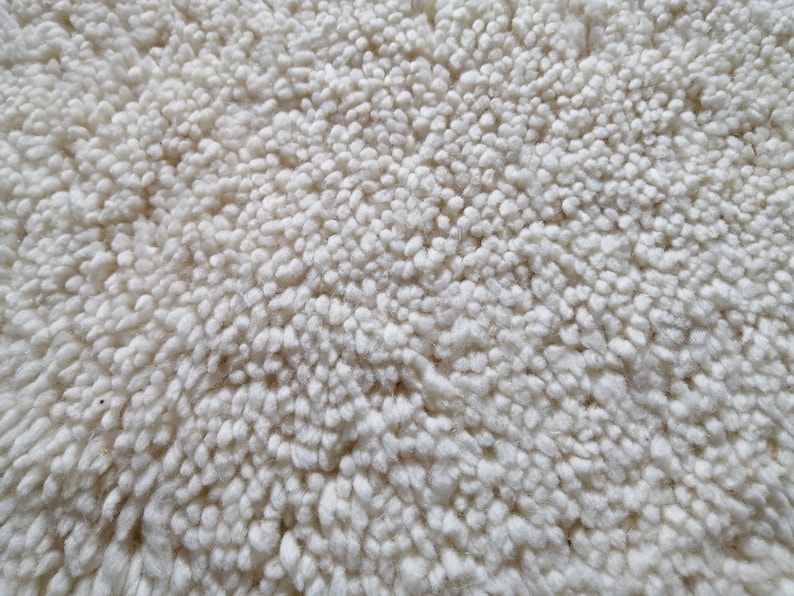 May include: Close-up of a white, fluffy rug with a soft, textured surface.