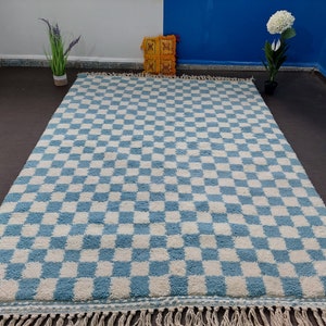 May include: A blue and white checkered rug with a fringe border. The rug is made of a soft, fluffy material.