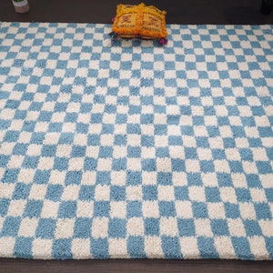 May include: A blue and white checkered rug with a fringe border. The rug is made of a soft, fluffy material.