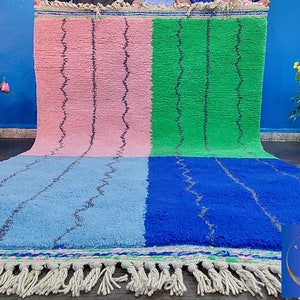 May include: A colorful Moroccan rug with a pink, green, blue, and light blue pattern. The rug has a fringe border and is made of wool.