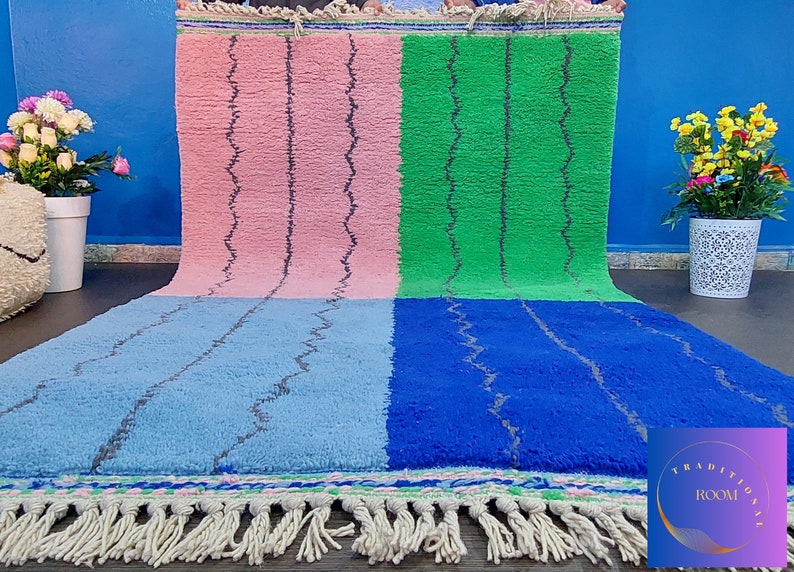 May include: A colorful Moroccan rug with a pink, green, blue, and light blue pattern. The rug has a fringe border and is made of wool.