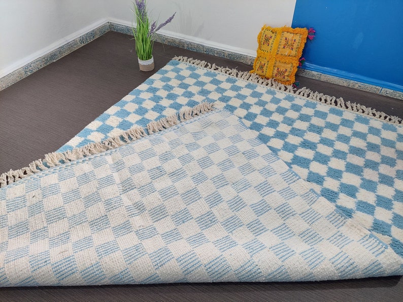 May include: Two blue and white checkered rugs with a fringe border. The rugs are made of a soft, fluffy material and are perfect for adding a touch of style to any room.