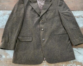 May include: A brown tweed blazer with a herringbone pattern and three buttons. The blazer has a single chest pocket and two front pockets.