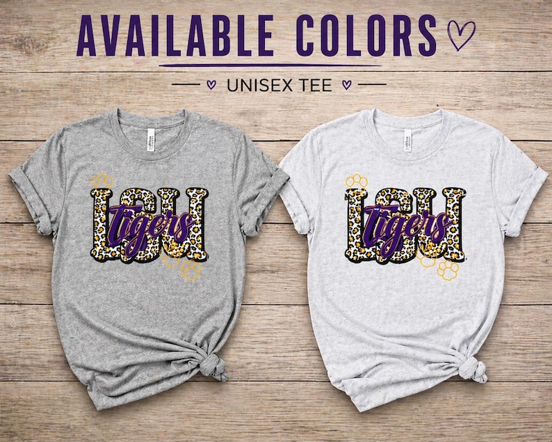 May include: Two unisex t-shirts, one gray and one white, with the text "LSU Tigers" in a leopard print design. The text "AVAILABLE COLORS" is at the top of the image.