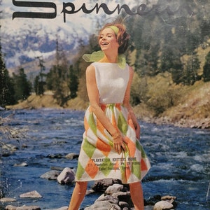 May include: A woman wearing a white and orange knitted dress with a green headband stands in a river with rocks. The text "PLANTATION KNITTERS" is visible on the dress. The text "International Preference" is visible at the bottom of the image.