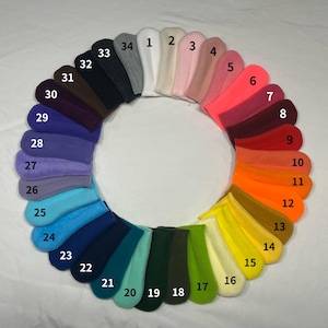 May include: A color wheel of 34 small, sock-like items, each in a different solid color. Colors range from white to black, including shades of pink, red, orange, yellow, green, blue, and purple. Each item is numbered for easy reference.