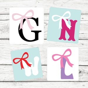 May include: Four square stickers with a letter and a pink bow on each. The letters are G, N, W, and L. The letters are in different colors and styles.