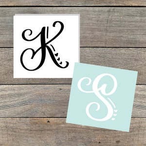 May include: Two white vinyl decals with black lettering. The first decal features the letter K with a heart design. The second decal features the letter S with a heart design.