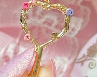 May include: A gold heart-shaped necklace with a delicate branch design and pink and purple flower accents.