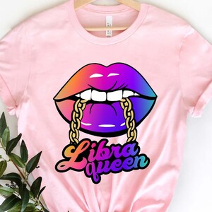 K&ouml;nnte beinhalten: Pinkes T-Shirt mit einem Regenbogen-Lippen-Design und einer goldenen Kette. Der Text "Libra Queen" ist unter den Lippen gedruckt.