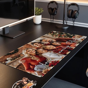 May include: A personalized Christmas-themed mousepad with a photo of a family in front of a decorated fireplace. The text "Joy to our family" is written in cursive on the mousepad. The mousepad is black with a red and white border.