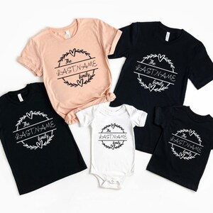 May include: Set of five black and peach t-shirts with a white graphic design. The graphic features a wreath with the text "The LASTNAME family".