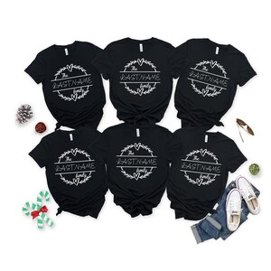 May include: Six black t-shirts with a white circle design featuring the text "The LASTNAME family" on each shirt.