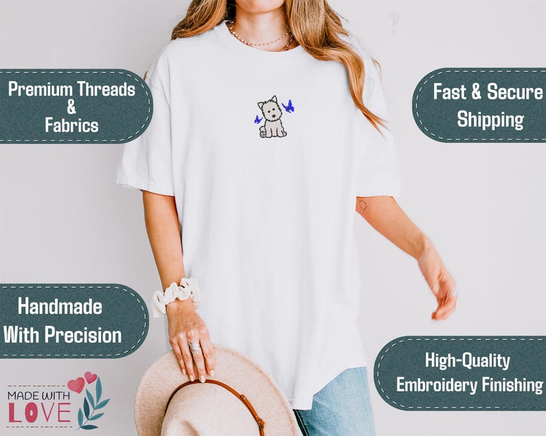 May include: White t-shirt with an embroidered West Highland White Terrier and two blue butterflies. The shirt features the text "Premium Threads & Fabrics", "Handmade With Precision", "Made With Love", and "High-Quality Embroidery Finishing".