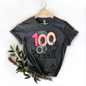 May include: A dark gray t-shirt with a colorful graphic that says "Happy 100th day of school".