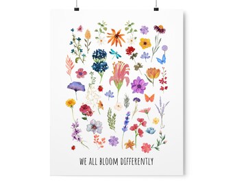 May include: A watercolor illustration of a variety of flowers in different colors, including pink, red, purple, blue, yellow, and orange. The flowers are arranged in a circular pattern and surrounded by butterflies and dragonflies. The text "We all bloom differently" is printed at the bottom of the image.