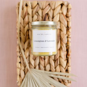 May include: A glass jar candle with a gold lid and a white label that reads "Basic Bee Candle Co. Lemongrass & Lavender Pure Beeswax - Organic Coconut Oil - Essential Oils"