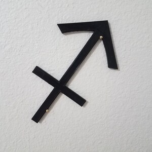 May include: Black metal Sagittarius zodiac sign wall decor with gold accents.