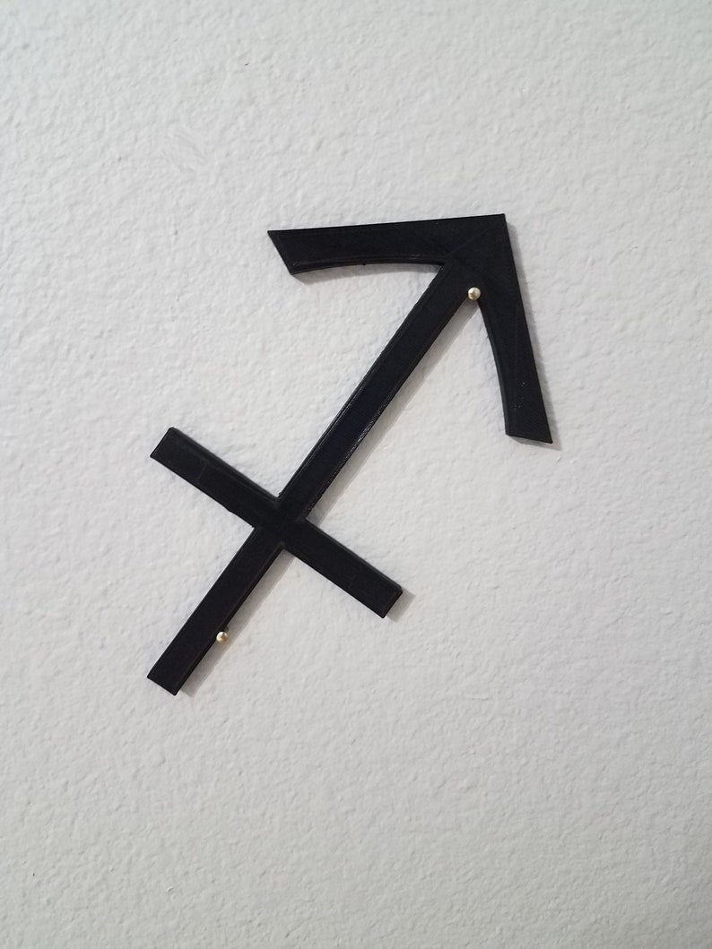 May include: Black metal Sagittarius zodiac sign wall decor with gold accents.