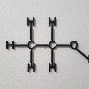 May include: A black plastic model of a chemical molecule with the letters 'H' and 'O' attached to the structure.