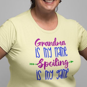 May include: A light yellow t-shirt with the text "Grandma is my name Spoiling is my game" in purple, blue, and green lettering.