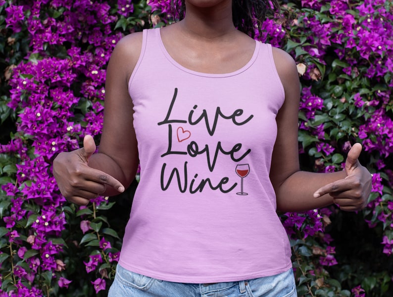 May include: A pink tank top with the text "Live Love Wine" in black script. A small red heart is above the word "Love" and a glass of red wine is next to the word "Wine".