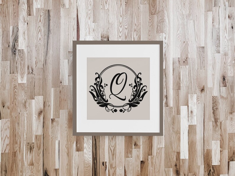 May include: A framed print with a black and white design of a stylized letter Q surrounded by floral elements. The letter Q is inside a circle and the floral elements are on the outside of the circle. The background of the print is a light beige color.