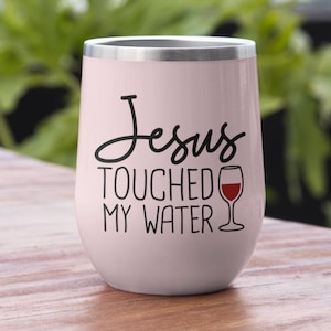 May include: A pink stainless steel tumbler with a black and white graphic that says "Jesus Touched My Water" and a red wine glass graphic.