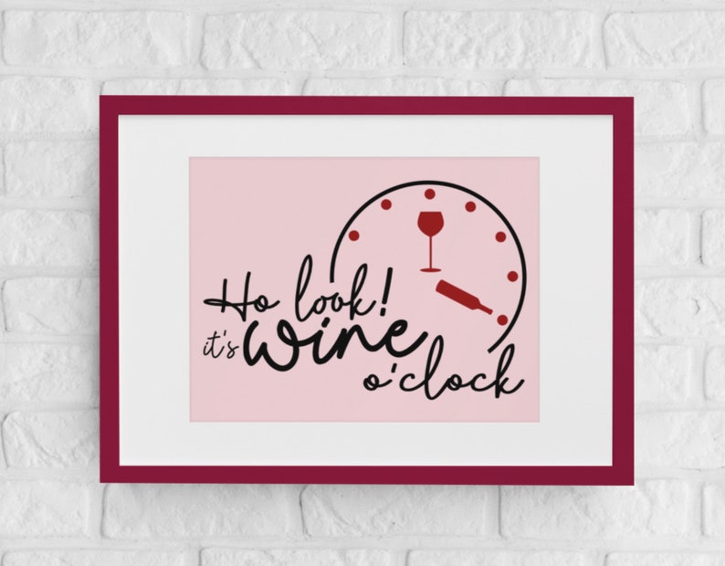 May include: A pink framed print with a black and white clock face with a wine glass and bottle on it. The text reads "Ho look! It's wine o'clock".