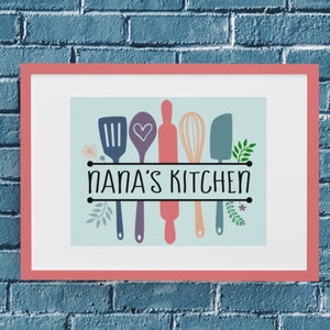 May include: A framed print with a light blue background featuring a spatula, spoon, rolling pin, whisk, and a spatula with a heart design. The text "NANA'S KITCHEN" is printed in black below the kitchen utensils.