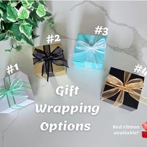 May include: Four gift boxes with different wrapping options are displayed. The boxes are white, gold, turquoise, and black, each adorned with a ribbon in various colors. Text on the image reads "Gift Wrapping Options."