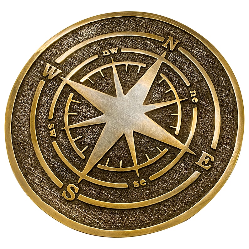 May include: A round, antique-style compass with a bronze finish. The compass rose features a central star design and directional markings: N, S, E, W, NE, NW, SE, and SW. The compass is set against a white background.