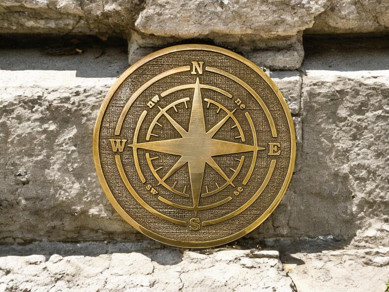 May include: A round, antique brass compass with directional markings (N, S, E, W) and a central star design. The compass is mounted on a weathered stone wall, showcasing a vintage nautical theme.