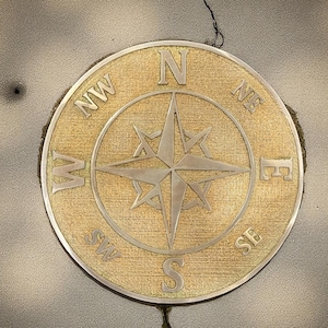 Peut inclure: Une rose des vents circulaire dorée avec des indications directionnelles (N, NE, E, SE, S, SW, W, NW) et une étoile centrale. La boussole est placée sur un fond texturé de couleur claire.