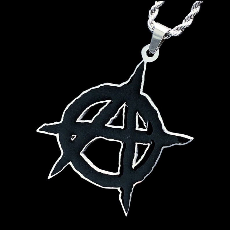 May include: A silver chain necklace with a black pendant featuring a stylized anarchy symbol.