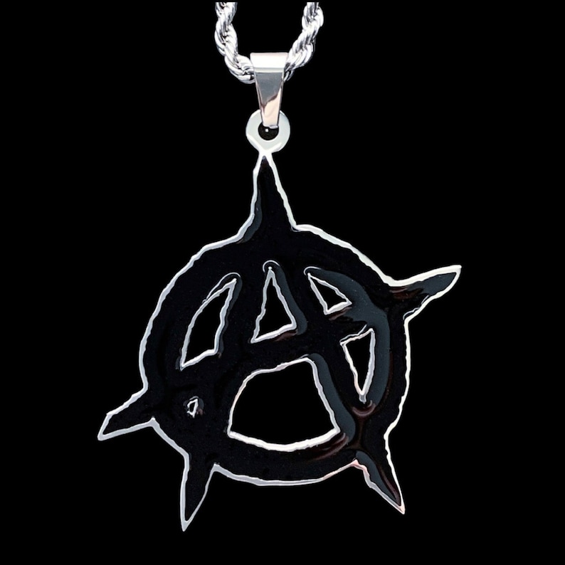 May include: A silver chain necklace with a black metal pendant featuring an anarchy symbol.