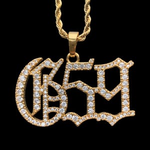 Può includere: Collana con catena dorata e ciondolo a forma del numero "659" con strass trasparenti.