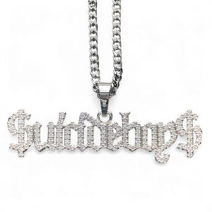 May include: Silver chain necklace with a pendant that says "Sideboys" in a gothic font, with each letter covered in small, clear rhinestones.