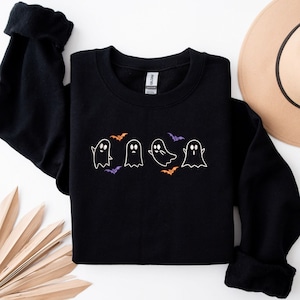 May include: Black sweatshirt with a white graphic of four ghosts and bats in orange and purple.