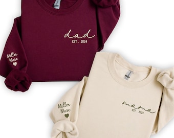 May include: Two matching sweatshirts, one burgundy and one cream, with the words "dad est. 2024" and "mama est. 2024" on the front. The sleeves have the words "Miller Mase" and a heart on them.
