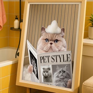 May include: A framed print showing a cat wearing a cloud-shaped hat and reading a newspaper titled "PET STYLE." The cat is in a bathtub with bubbles. The frame is light brown.