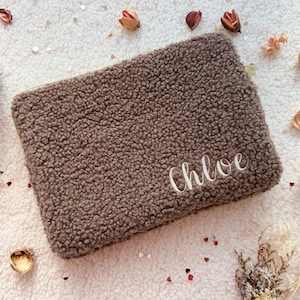 Könnte beinhalten: Eine rechteckige braune Sherpa-Tasche mit einer flauschigen, strukturierten Oberfläche. Der Name Chloe ist in weißer Schreibschrift in der unteren rechten Ecke der Vorderseite eingestickt. Die Tasche hat ein schlichtes, klares Design.