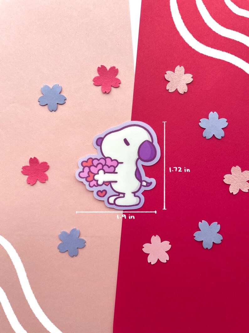 May include: A sticker featuring a cartoon character holding a bouquet of hearts, surrounded by pink and blue flower-shaped cutouts. The sticker is 1.9 inches wide and 1.72 inches tall. The background is split between pink and red.