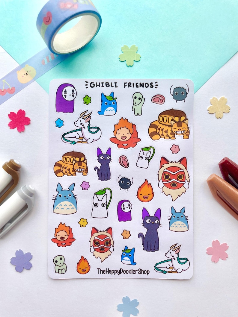 May include: A sheet of stickers featuring characters from Studio Ghibli films. The stickers are colorful and feature characters like Totoro, No Face, and Kiki's Delivery Service. The sheet is titled "Ghibli Friends" and includes the text "The Happy Doodler Shop".
