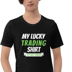 May include: A black t-shirt with white text that reads "My Lucky Trading Shirt" and a green banner that reads "Do Not Wash".