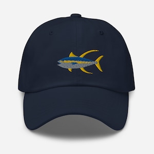 Könnte beinhalten: Eine marineblaue Baseballkappe mit einem gestickten gelben und blauen Thunfisch-Design.