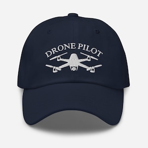May include: A navy blue baseball cap with white embroidery that reads "DRONE PILOT" and a stylised drone graphic.