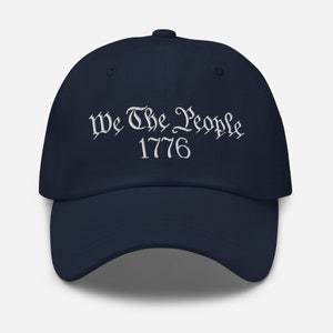 May include: A navy blue baseball cap with white embroidery that reads "We The People 1776".