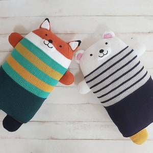 May include: Two plush toys, one a fox with orange and green stripes and a green belly, the other a white bear with black and white stripes and a navy blue belly.